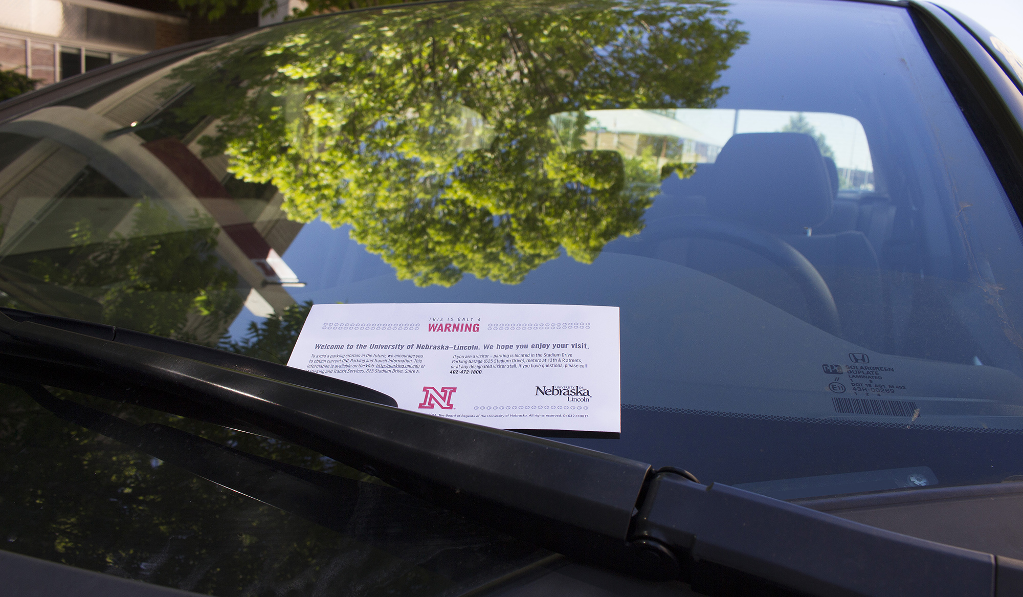Warning letter from parking enforcement tucked under car wiper